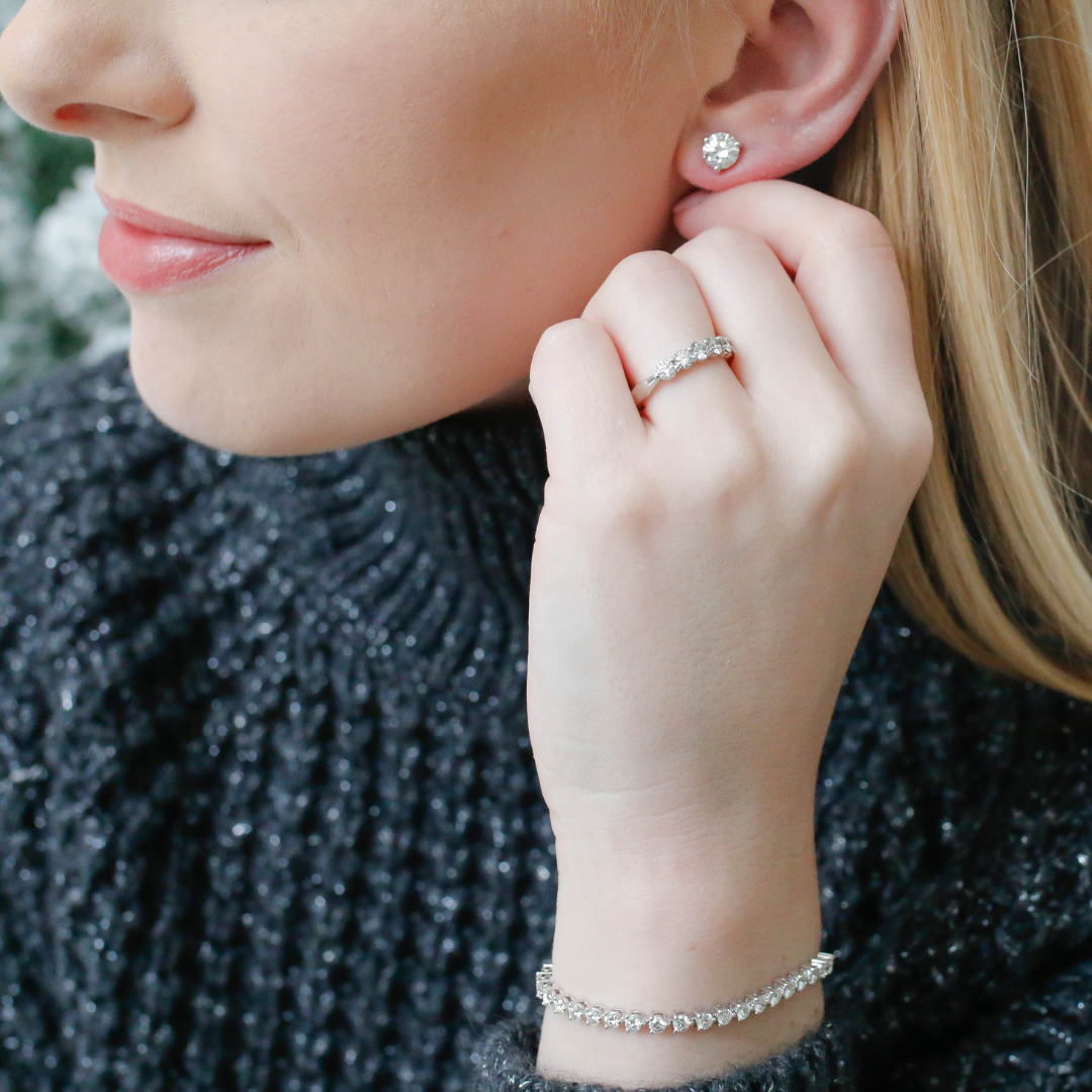 Woman wearing Hearts on Fire diamond stud earrings, ring, and bracelet