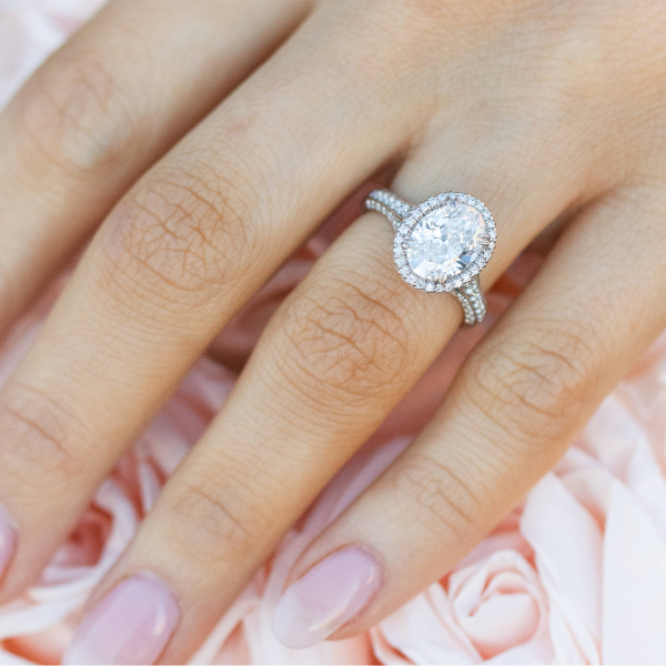 up close of an oval engagement ring on someone's hand