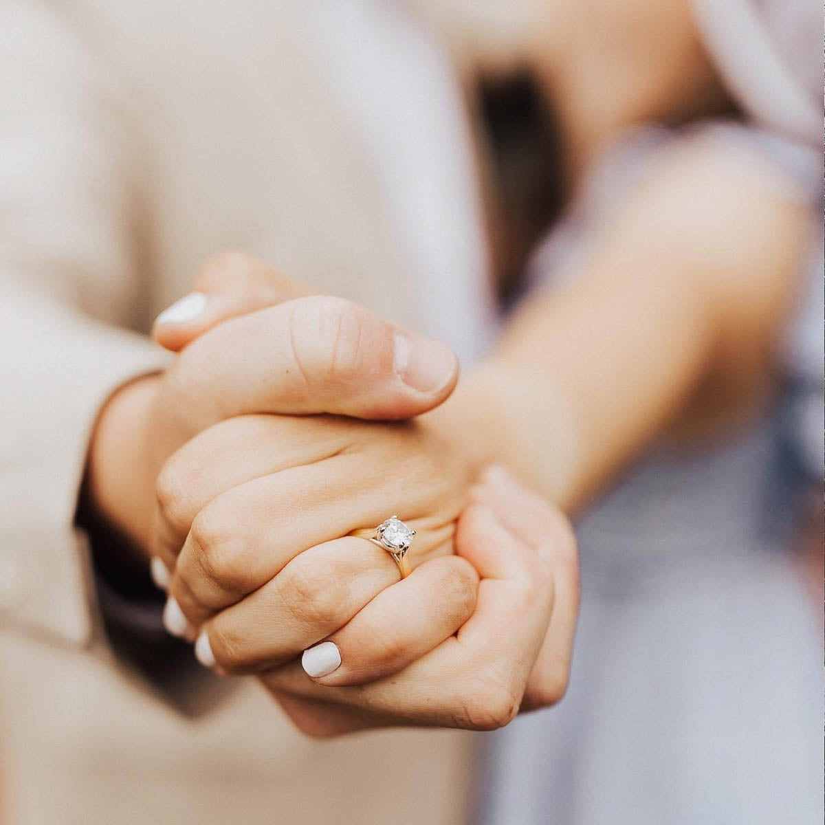 a couple holding hands showing off an engagement ring